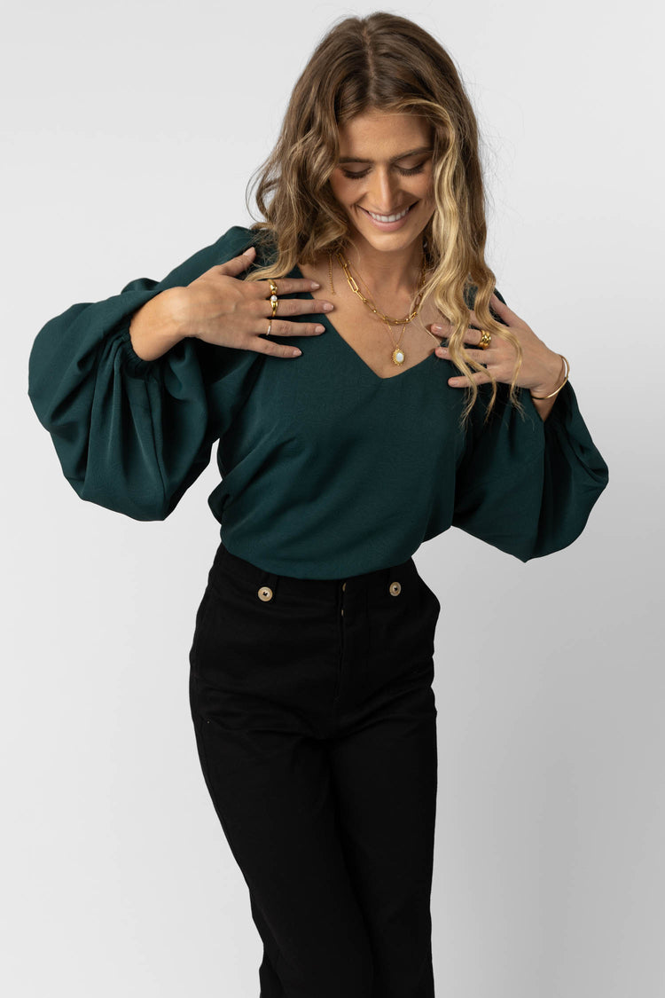 model wearing jade long sleeve blouse with balloon sleeves paired with black wide leg pants