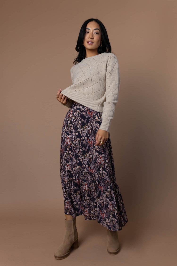 model wearing floral midi skirt paired with cream sweater and tan boots