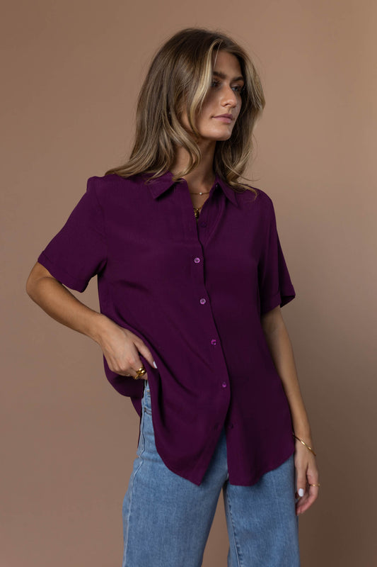 Model wearing plum short sleeve button down paired with light wash denim