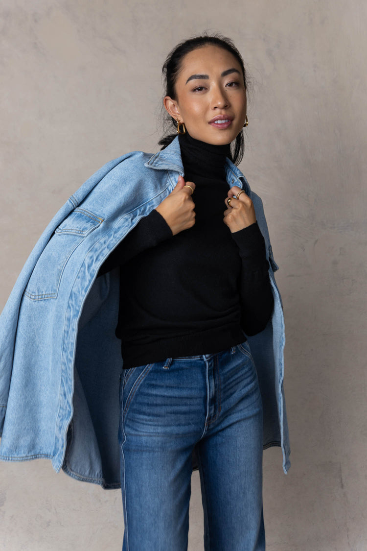 model wearing black turtle neck sweater layered with denim jacket and paired with medium wash denim