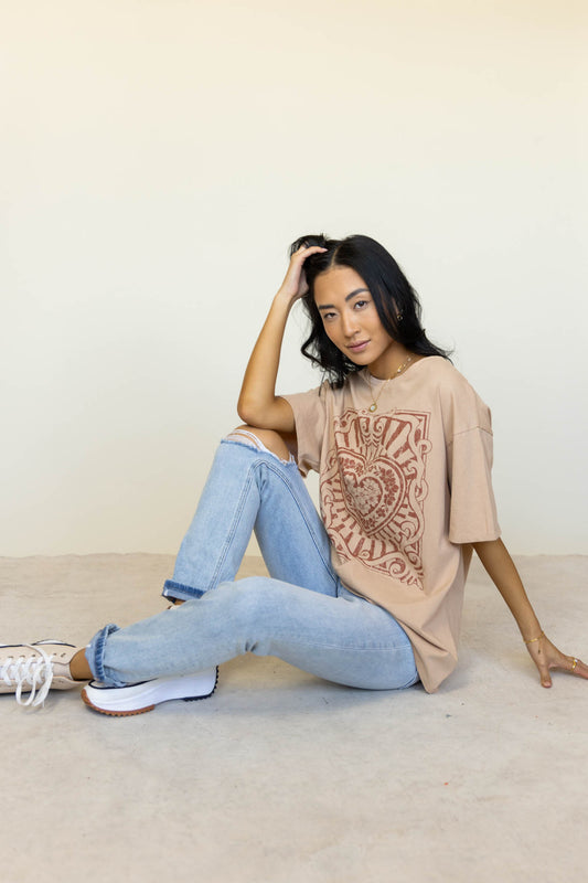 model wearing tan graphic tee paired with light wash distressed denim