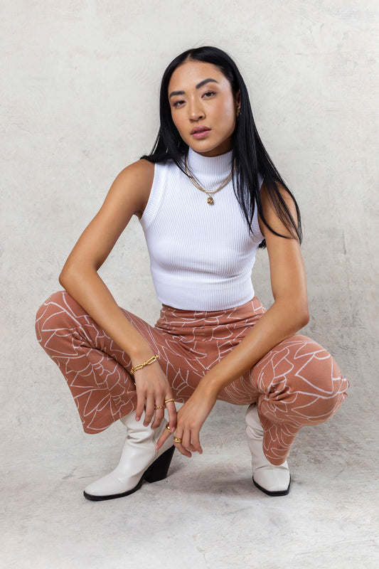 model wearing ribbed white mock neck tank top paired with patterned pants paired with white boots
