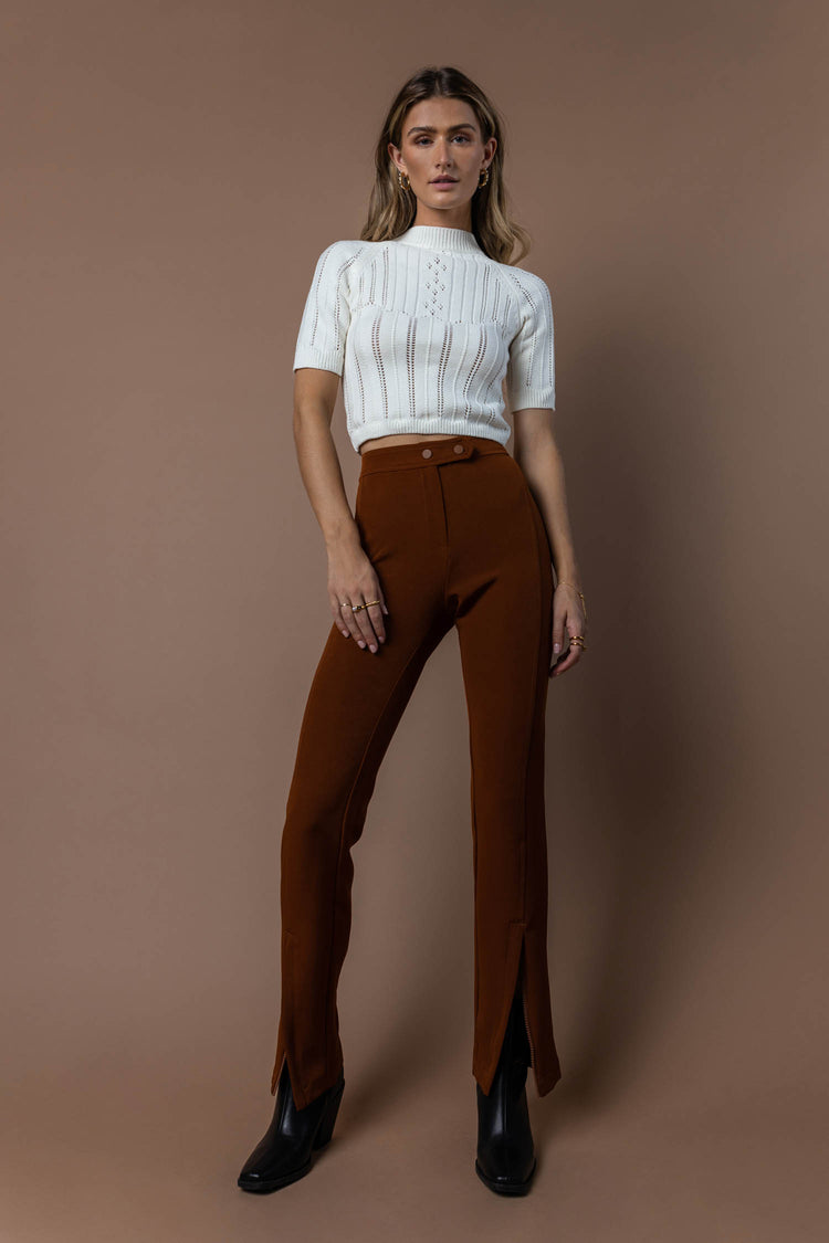 white crop top with brown skinny pants and black boots