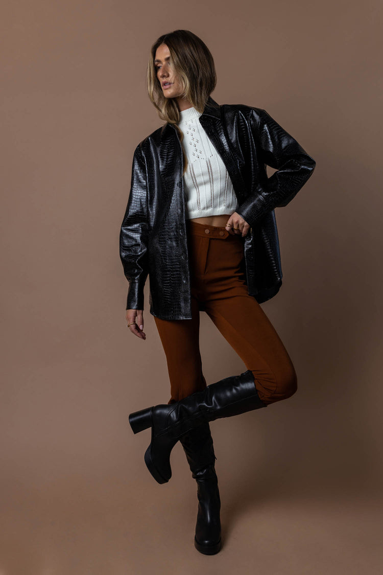 black jacket with white crop top, brown dress pants and black knee high boots