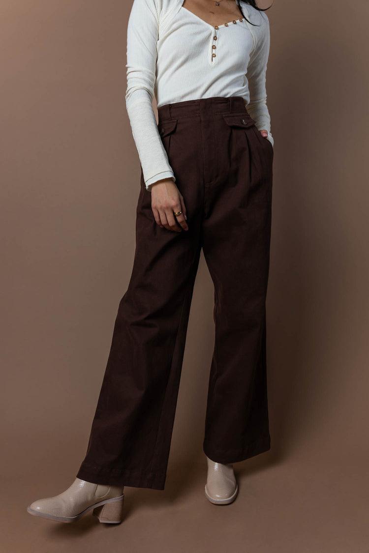 model wearing brown wide leg pants with front pleat details paired with cream boots