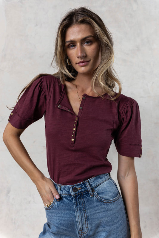 model wearing burgundy short sleeve tee with front and sleeve button details 
