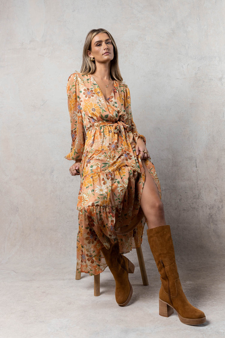 model wearing tangerine floral printed midi dress with v-neck and long balloon sleeves paired with brown boots