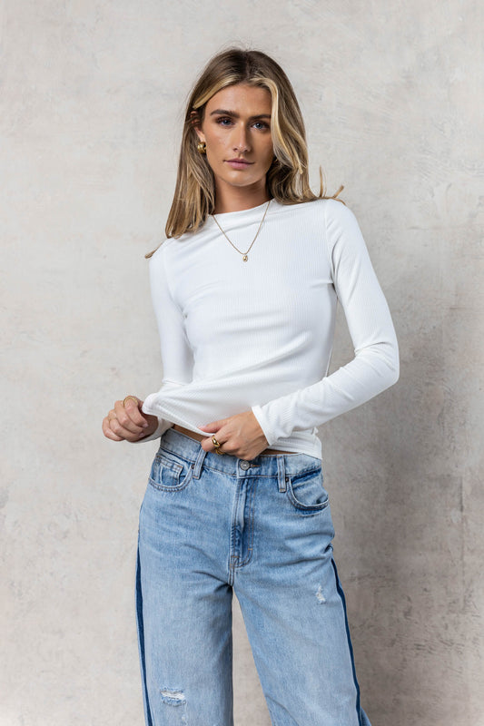 model wearing white long sleeve ribbed mock neck paired with light wash denim