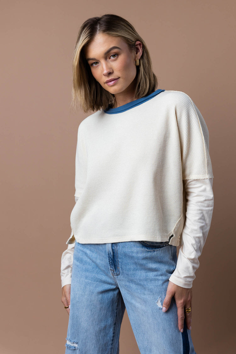 model is wearing a waffle knit top with jeans.
