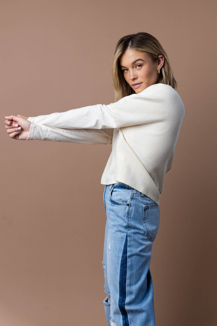 model is wearing a waffle knit top with jeans.