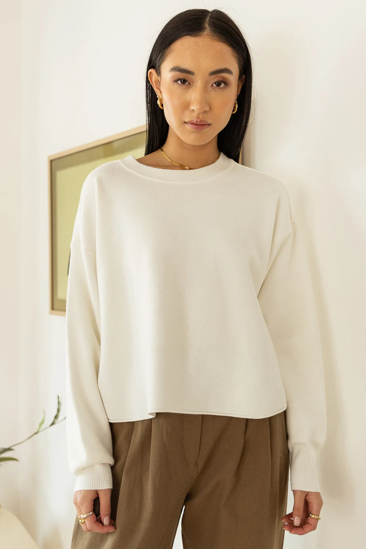 long sleeve cream sweater paired with trousers