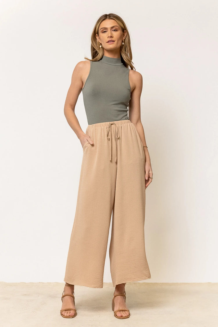 sage green sleeveless bodysuit paired with tan pants