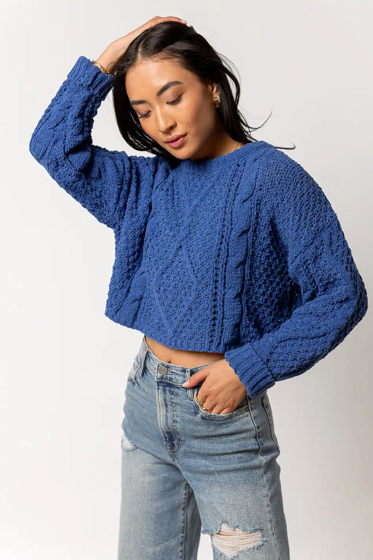 blue cable knit sweater paired with distressed denim