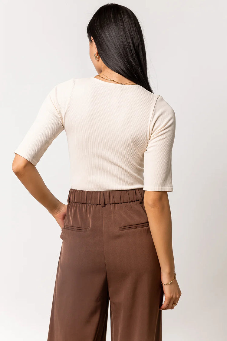 cream short sleeve bodysuit paired with brown trousers